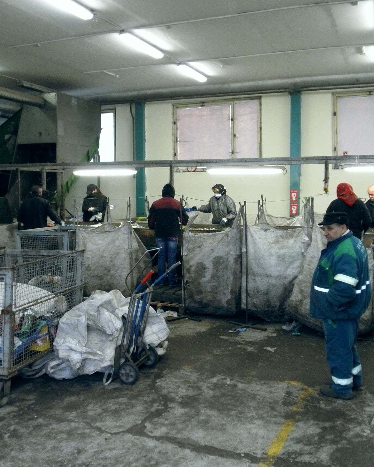 Operarios con chaleco reflectivo clasificando material aprovechable en puestos de trabajo.